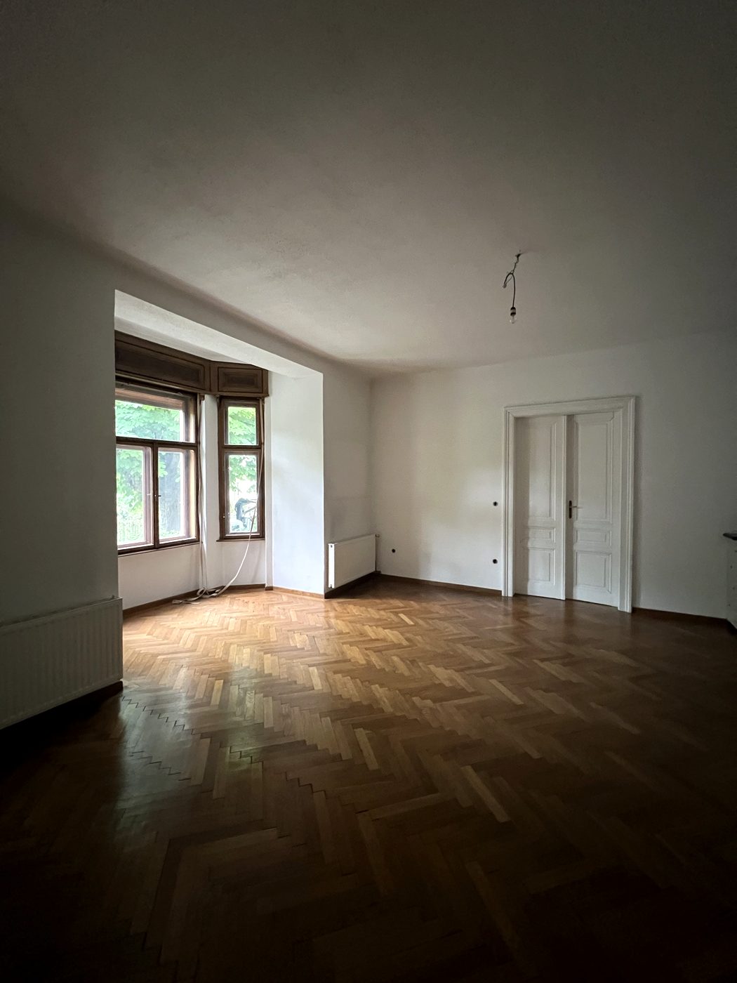 Zimmer mit Erker schräg fotografiert: Erker, Heizkörper, Flügeltür