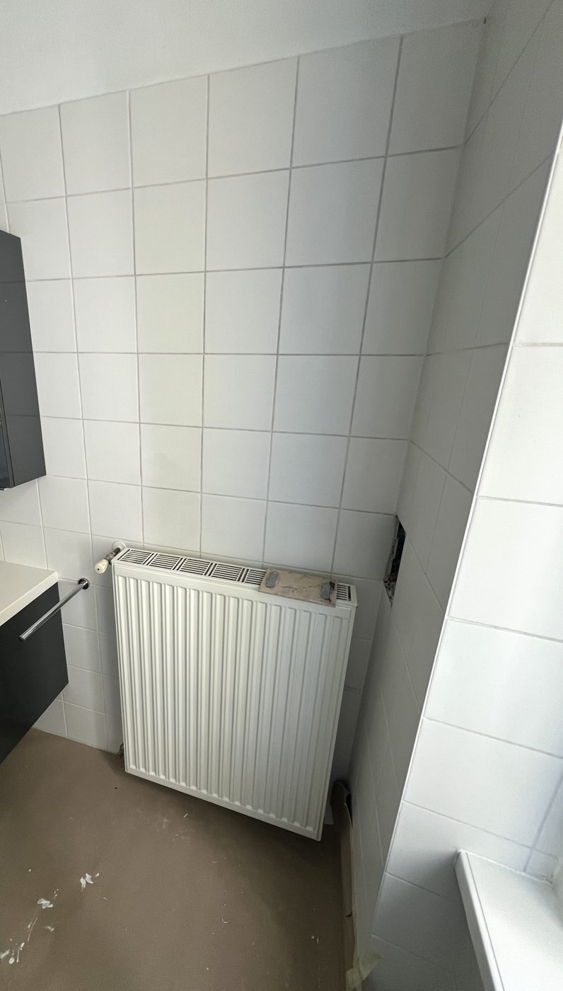 Bad mit dem Heizkörper in der Ecke, daneben der Waschtisch